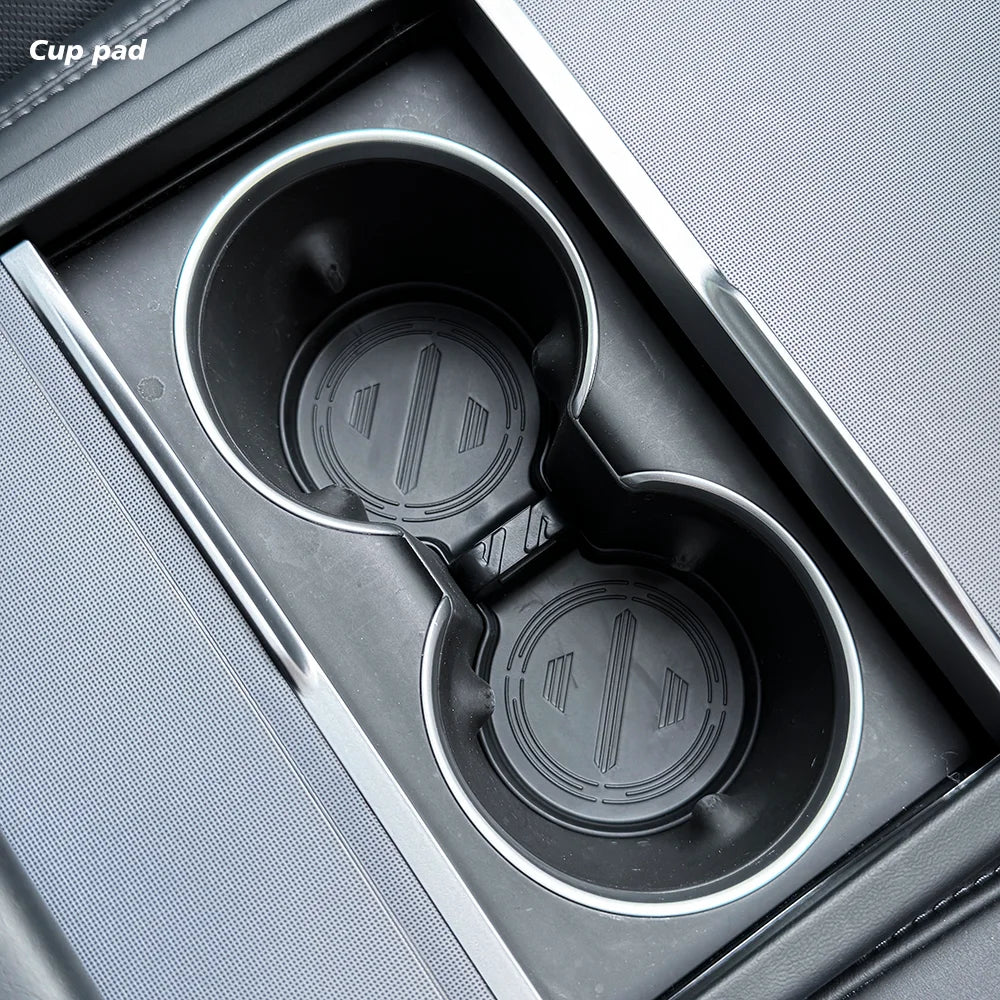 Car cup holder with a black cup pad in a gray car console.